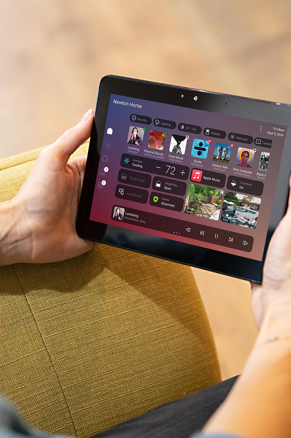 Hands holding a tablet displaying a smart home control dashboard with various settings