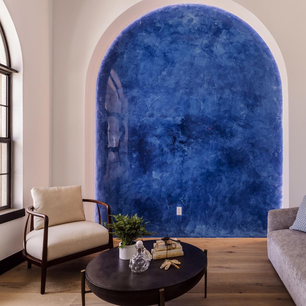 Cozy seating area featuring a deep blue textured arched wall and a dark oval coffee table