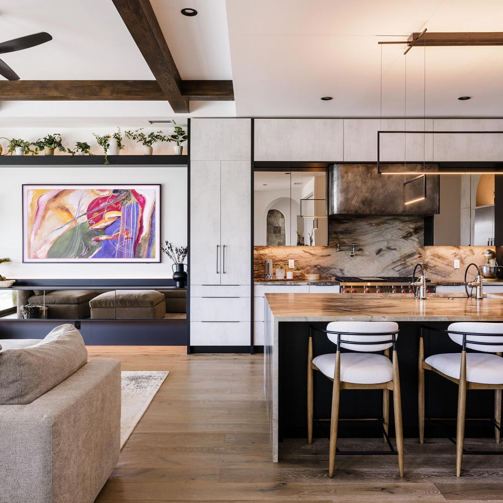 Modern open kitchen and living area with a marble island and colorful abstract art on the wall