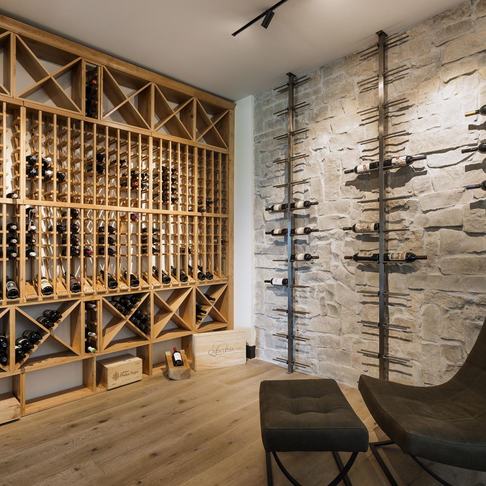 Modern wine cellar with wooden storage racks a textured stone wall and a dark leather chair