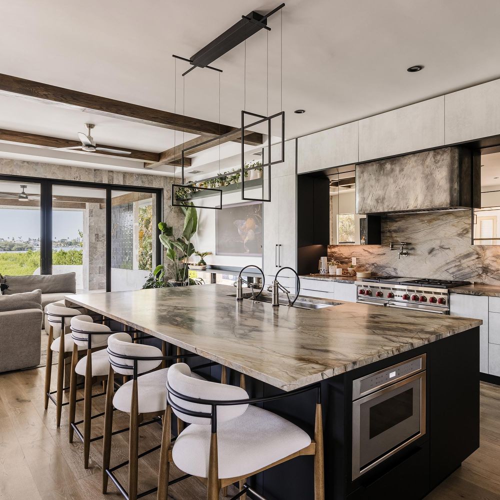 Modern kitchen with a large marble island upholstered bar stools and sliding doors to a patio